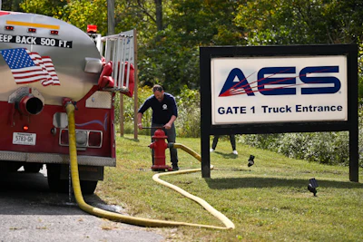 A person attaches a hose to a fire hydrant to fill a tanker truck after a blast resulted in multiple fatalities and others missing at Accurate Energetic Systems, an explosives plant, Friday, Oct. 10, 2025, in Bucksnort, Tenn.