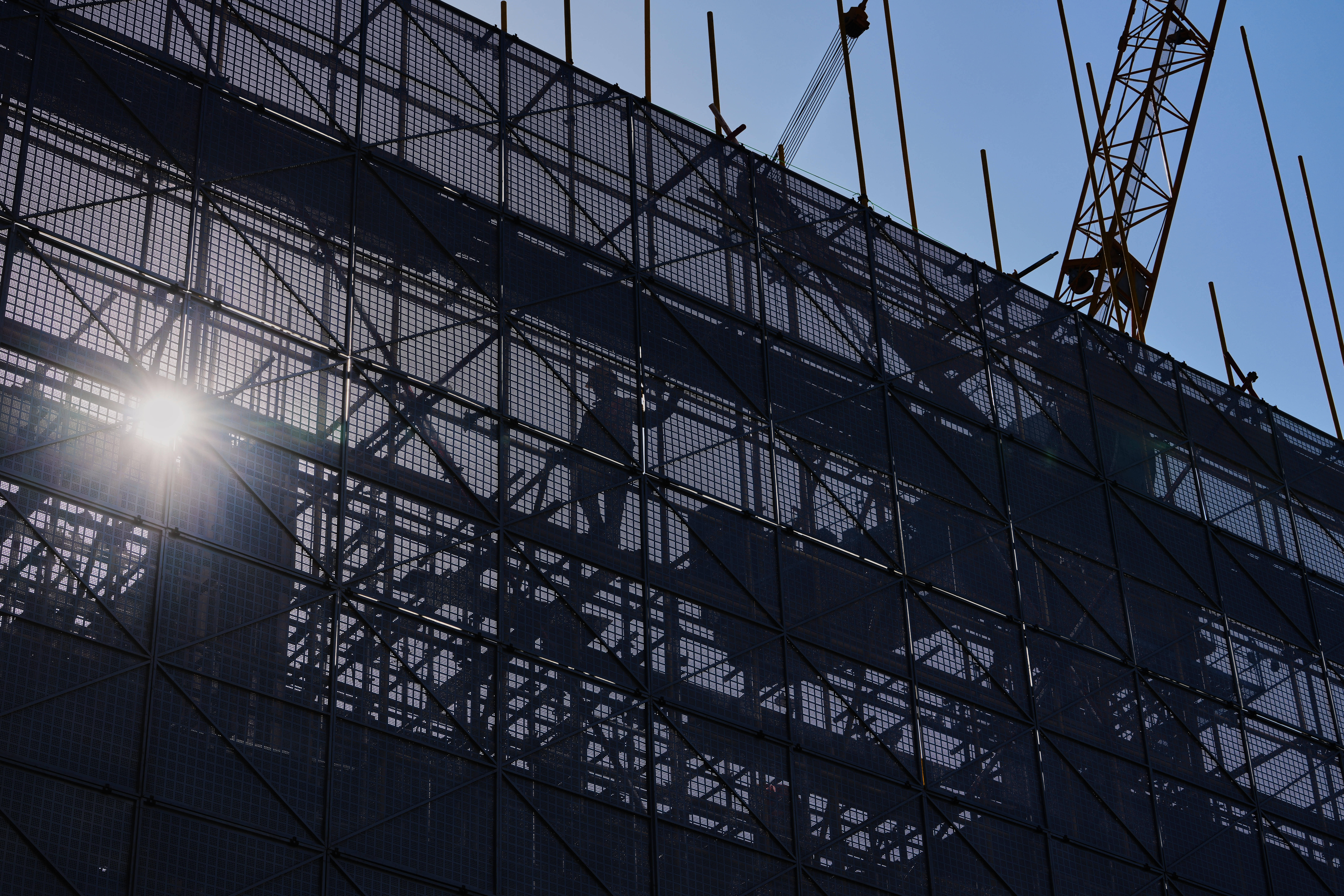 A worker installs scaffolding at a building under construction at the capital popular shopping district, in Beijing, Tuesday, Oct. 21, 2025.
