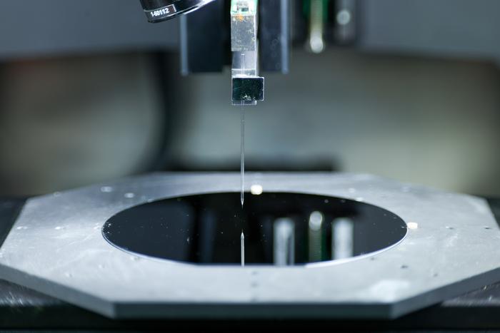 A closeup look at the tiny needle used in the Hummink printing technology. The needle is essentially attached to a tuning fork, which moves the needle rapidly above the printing surface. Natural competing surface energies pull tiny amounts of ink out to print designs with submicrometer precision.
