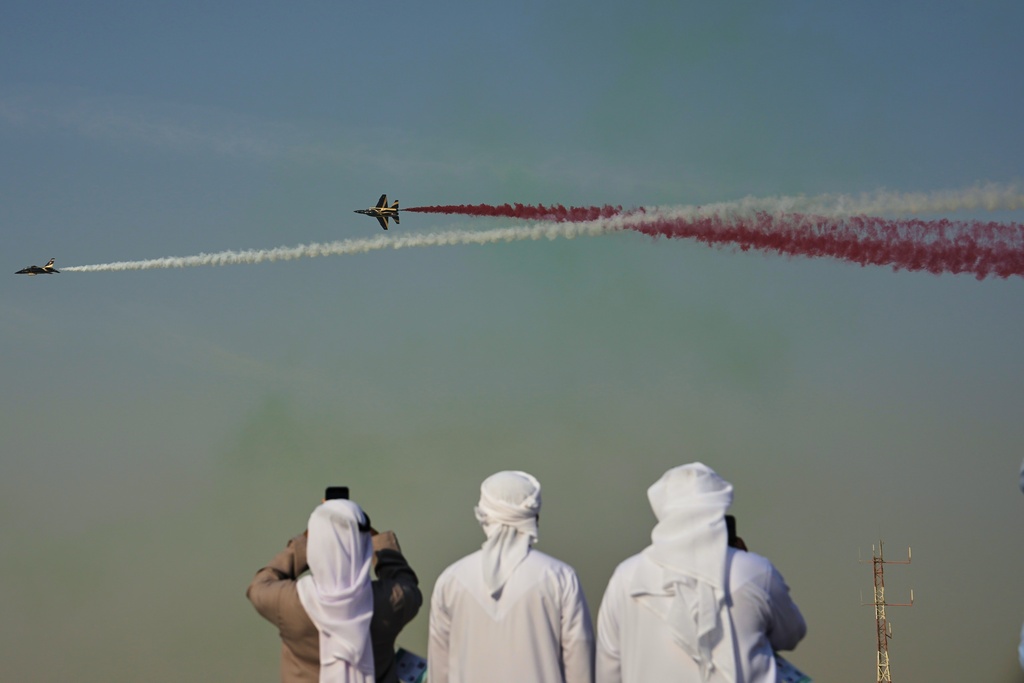 Emirati men take photos of Fursan Al Emarat, the aerobatics demonstration team of the United Arab Emirates Air Force during the Dubai Air Show in Dubai, United Arab Emirates, Tuesday, Nov. 18, 2025.