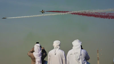 Emirati men take photos of Fursan Al Emarat, the aerobatics demonstration team of the United Arab Emirates Air Force during the Dubai Air Show in Dubai, United Arab Emirates, Tuesday, Nov. 18, 2025.