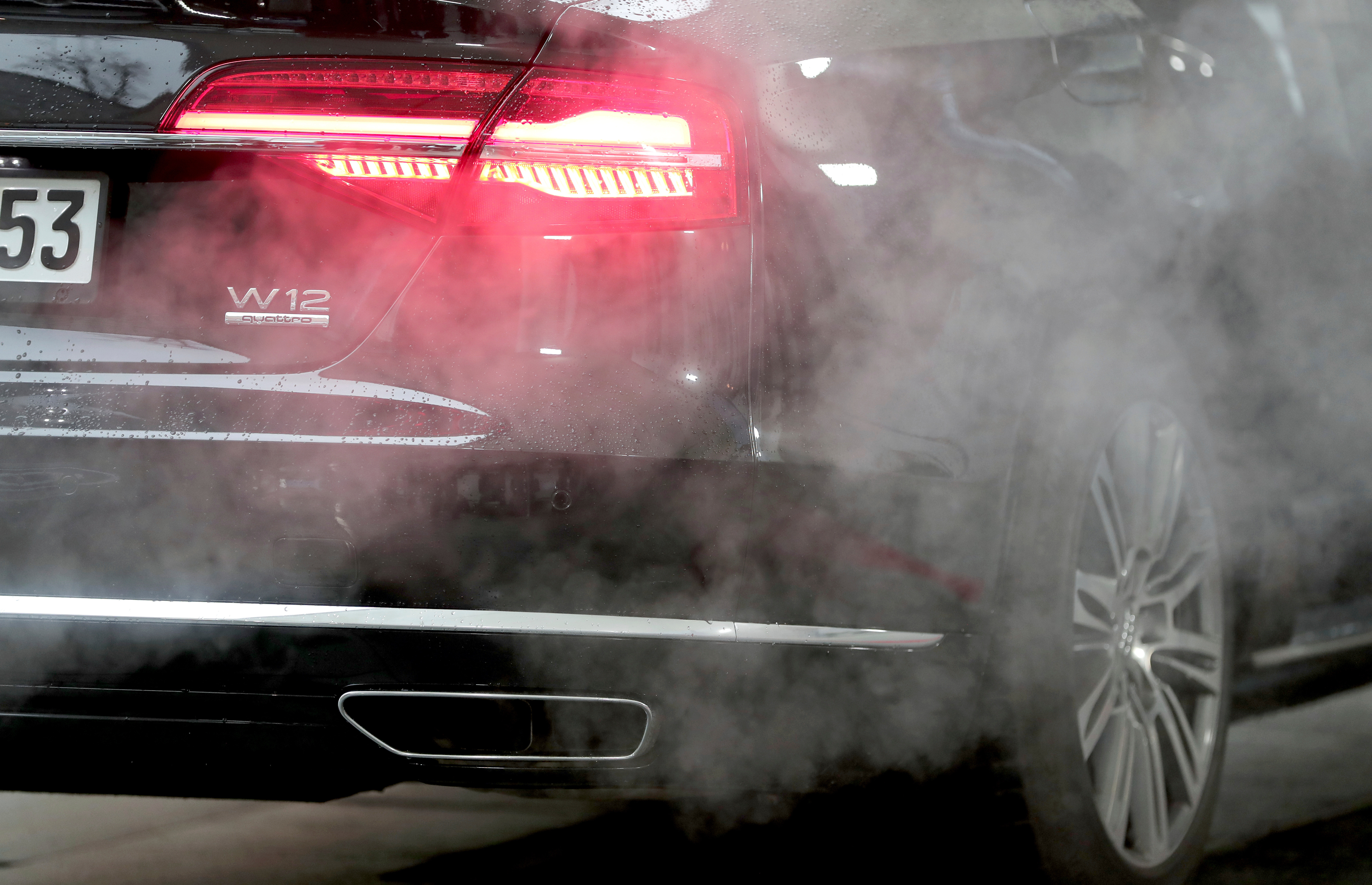 A luxury Audi car is surrounded by exhaust gases as it is parked with a running engine in front of the Chancellery in Berlin, Germany, Wednesday, Nov. 20, 2019.