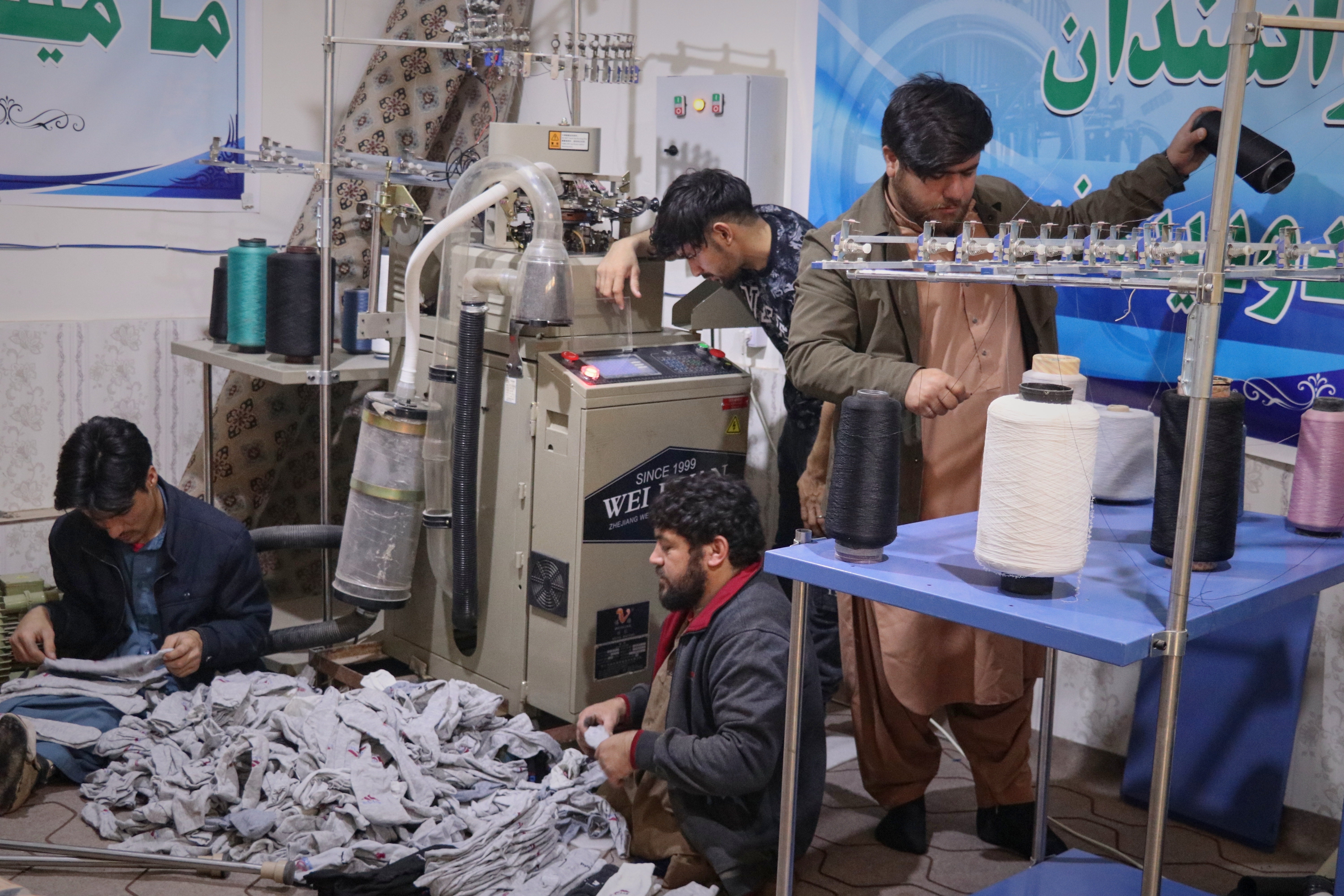 Local businessman Mohammad Amiri, 35, right, sorts out spools of thread for making socks as he works with his staff, all people with disabilities, in his sock production workshop in the western Afghan city of Herat, Afghanistan, Monday, Dec. 8, 2025.