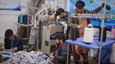 Local businessman Mohammad Amiri, 35, right, sorts out spools of thread for making socks as he works with his staff, all people with disabilities, in his sock production workshop in the western Afghan city of Herat, Afghanistan, Monday, Dec. 8, 2025.
