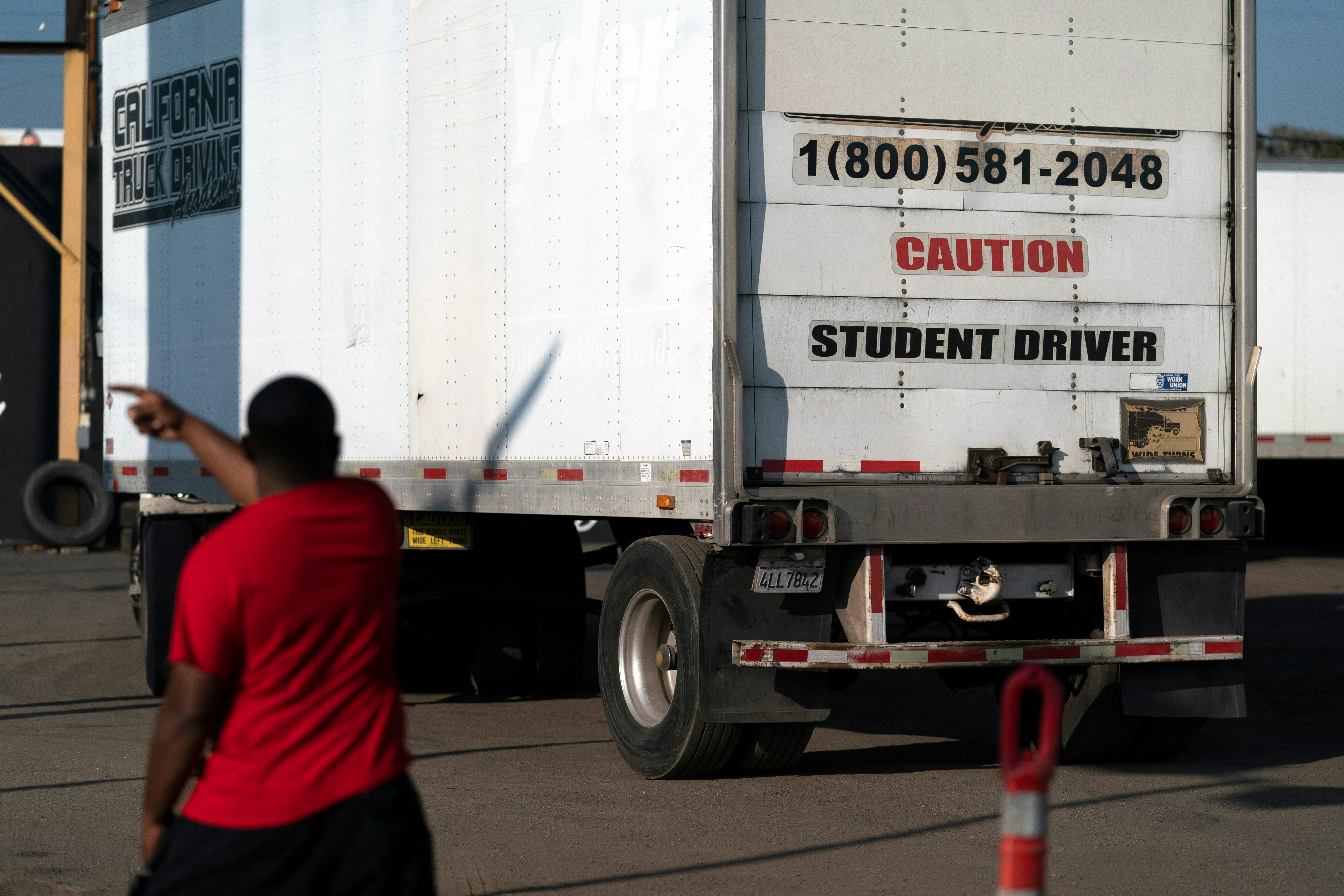 A student driver helps his classmate steer the wheel into the right direction as they practice driving in reverse in Calif., Nov. 17, 2021.