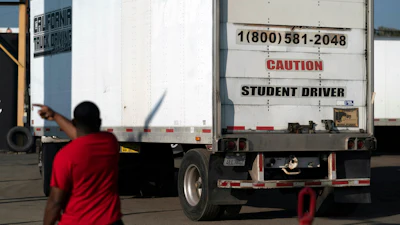 A student driver helps his classmate steer the wheel into the right direction as they practice driving in reverse in Calif., Nov. 17, 2021.