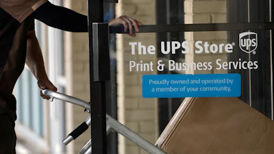 A UPS driver enters a United Parcel Service store with packages in Jackson, Miss., July 26, 2021.
