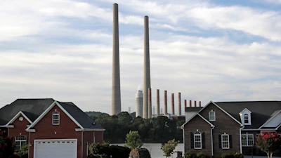The Kingston Fossil Plant smokestacks rise above the trees behind homes in Kingston, Tenn, Aug. 7, 2019.