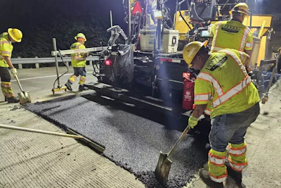 The construction team finishes up paving a stretch of road with plastic-infused pavement.