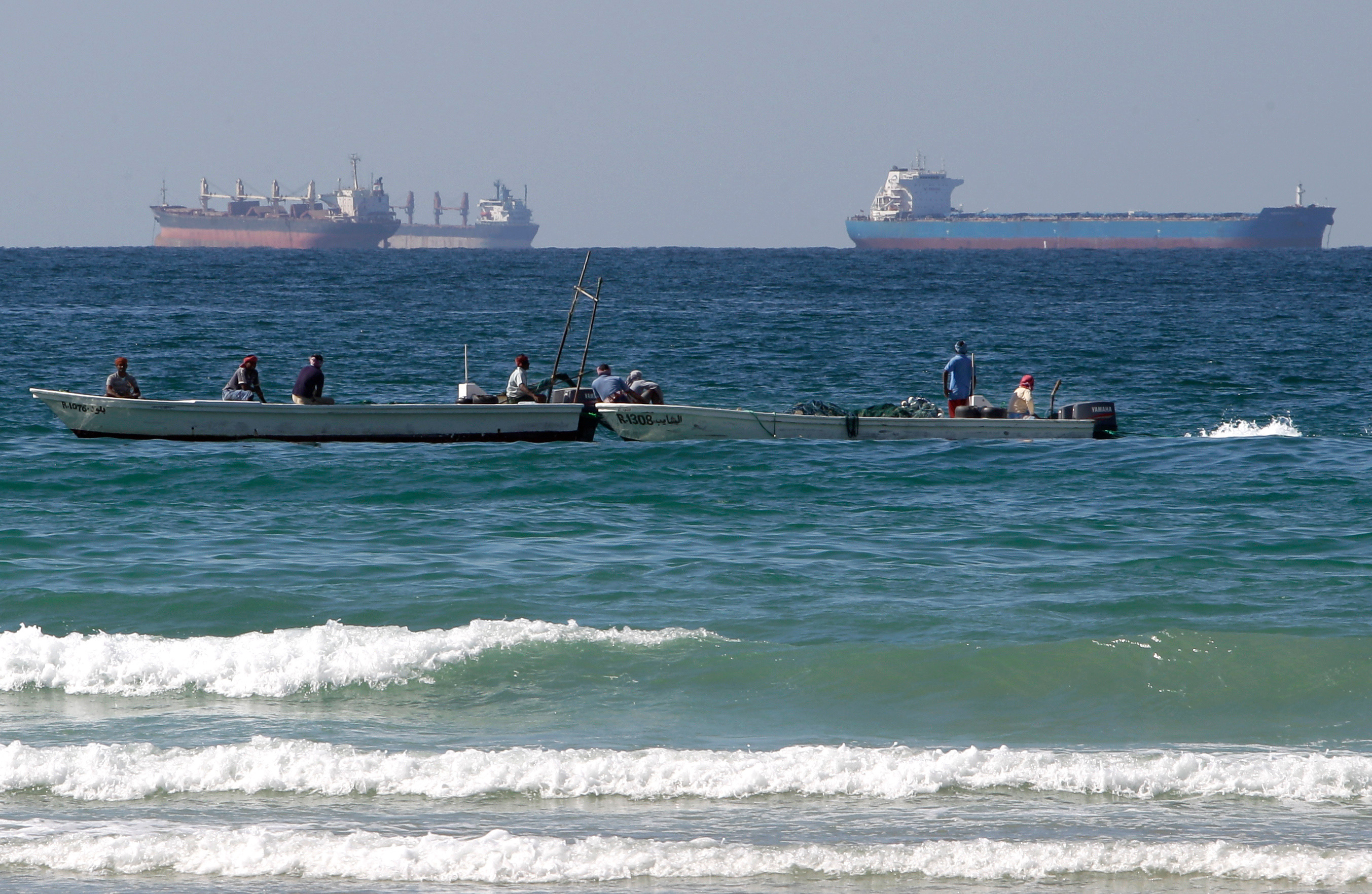 Fishermen work in front of oil tankers south of the Strait of Hormuz Jan. 19, 2012, offshore the town of Ras Al Khaimah in United Arab Emirates.