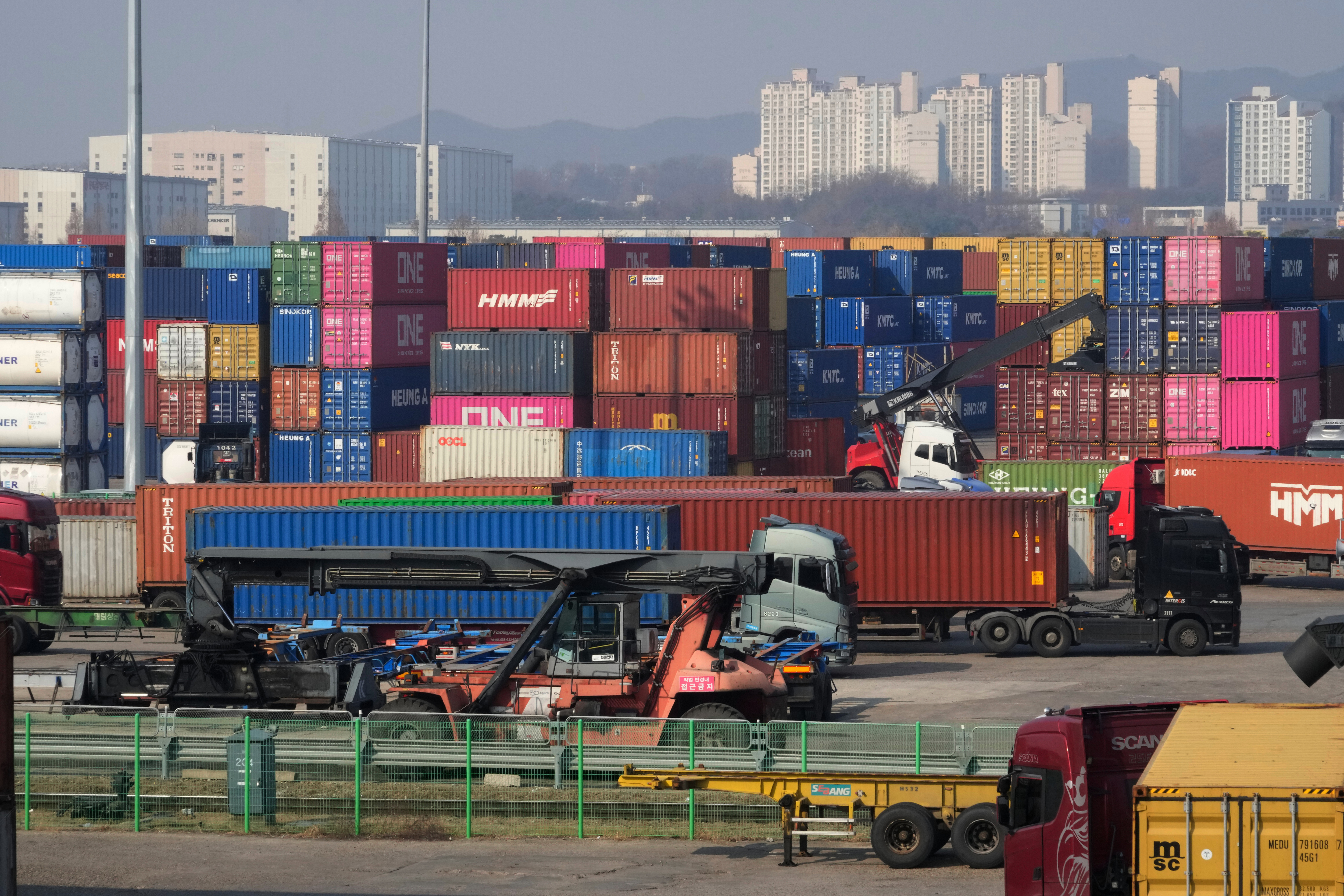 Trucks run by containers at the Uiwang ICD Terminal in Uiwang, South Korea, Thursday, March 12, 2026.