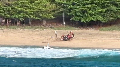 Kauai Ocean Safety members and other people assist individuals after an Airborne Aviation tourist helicopter crash on Kalalau Beach on Kauai, Hawaii, on March 26, 2026.