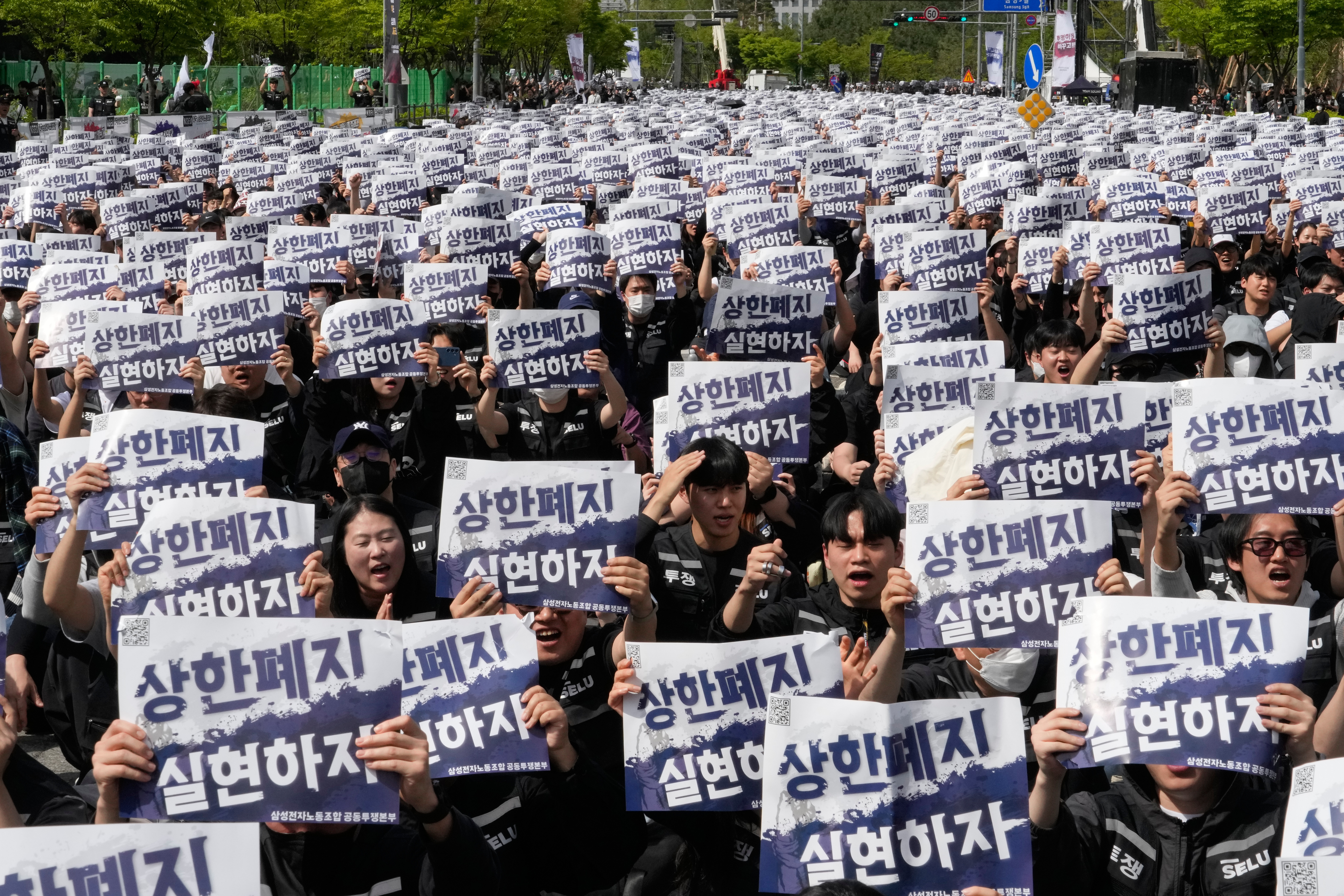 Members of the Samsung Electronics labor union hold up their cards during a rally demanding higher bonuses at its computer chip complex in Pyeongtaek, South Korea, Thursday, April 23, 2026. The letters read 'Remove the bonuses caps.'