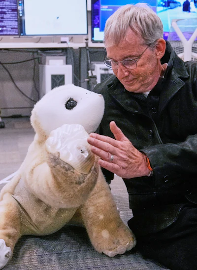Colin Angle, co-founder and former CEO of Roomba vacuum maker, interacts with a prototype AI robot at his Massachusetts-based startup Familiar Machines & Magic, Wednesday, April 29, 2026, in Woburn, Mass.