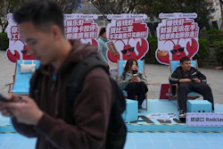 Shoppers rest at a RedClaw AI promotion booth outside a shopping mall in Beijing, March 28, 2026.