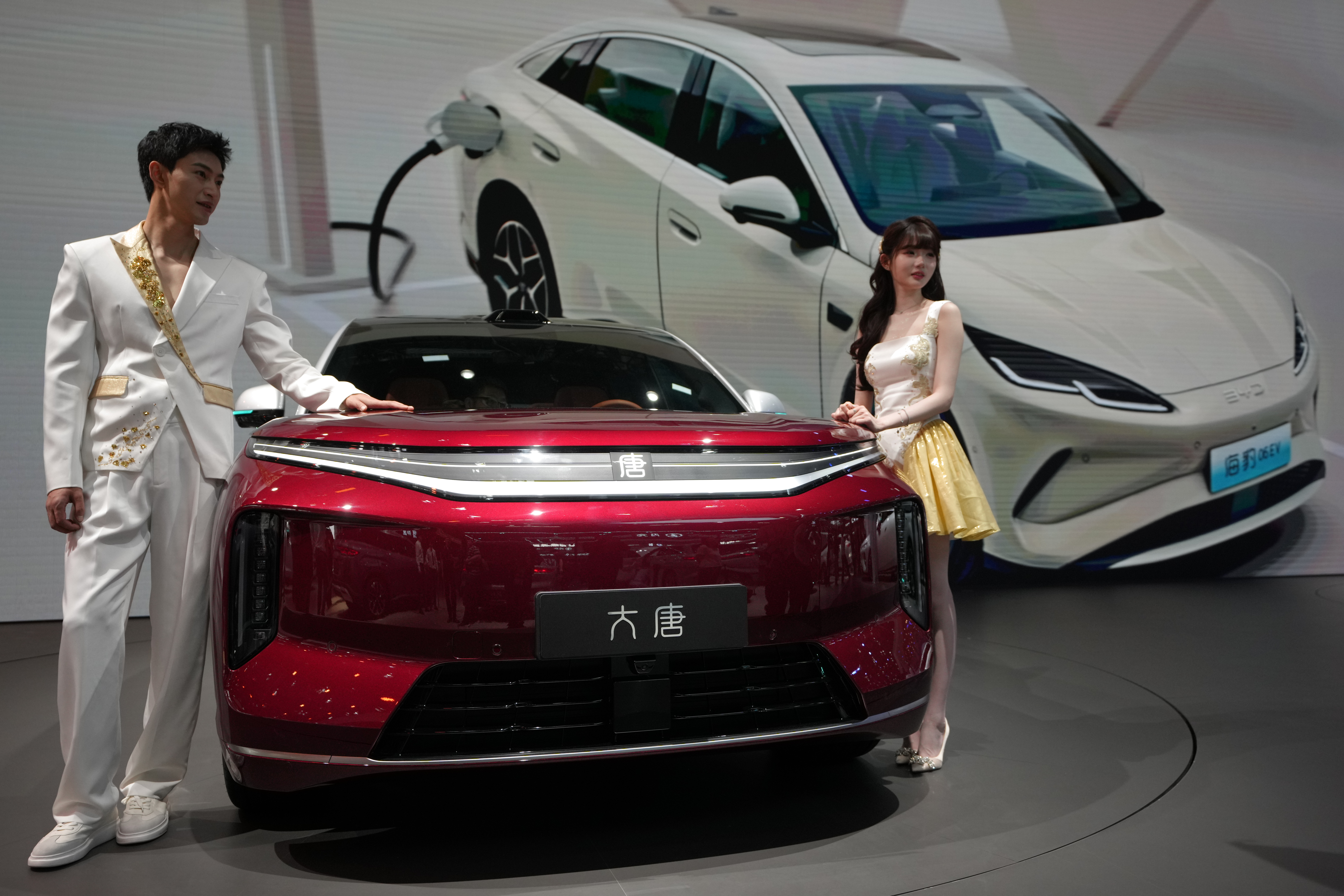 Models stand next to a latest EV car from Chinese automaker BYD showcased at the Auto China 2026, in Beijing, Saturday, April 25, 2026.