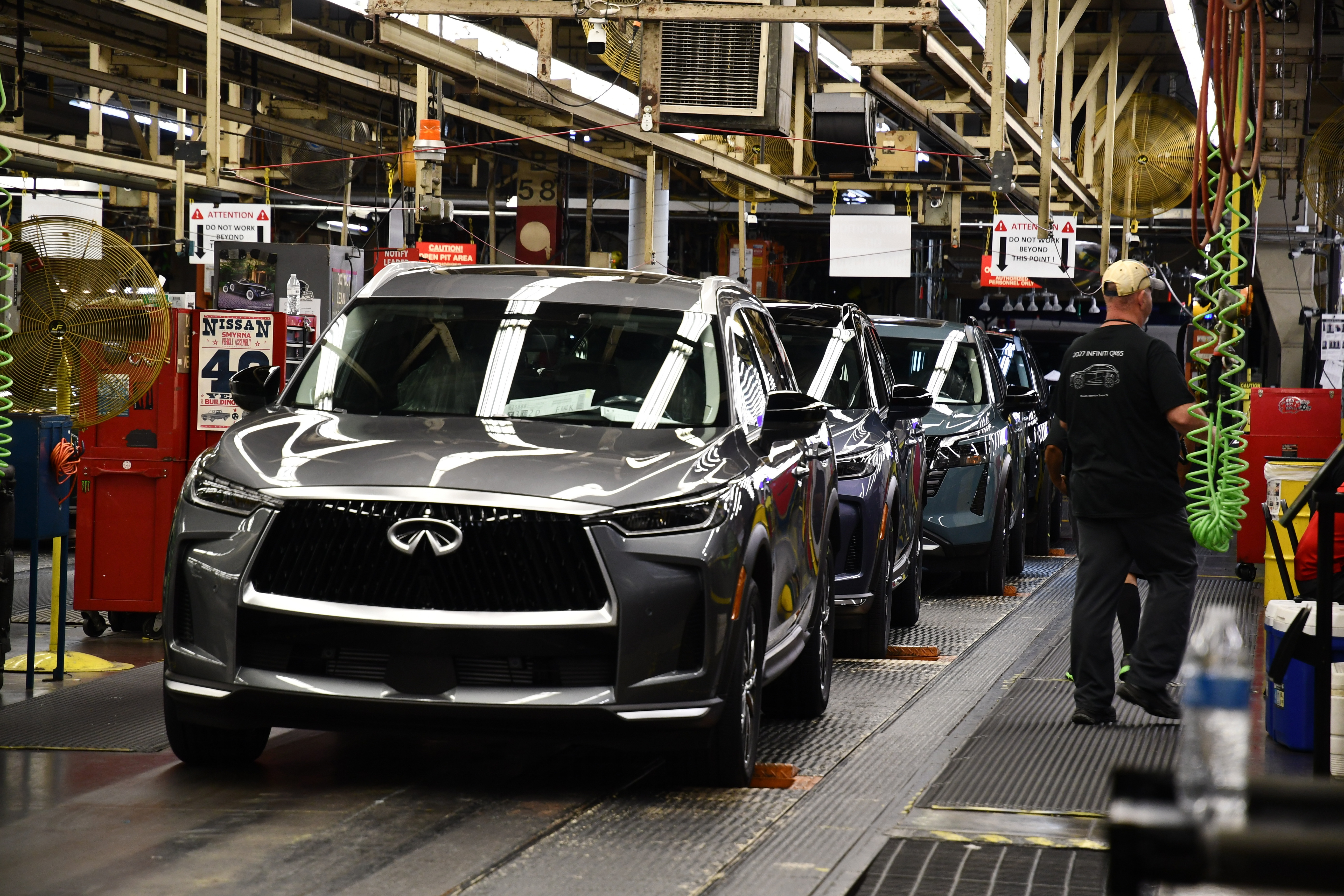 A worker walks past a line of Infiniti SUVs on a production line at the Nissan Smyrna Vehicle Assembly Plant, Thursday, April 16, 2026, in Smyrna, Tenn.