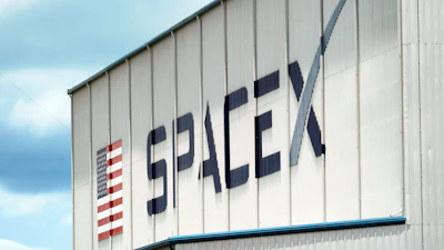 SpaceX logo with American flag symbol on industrial metal building exterior