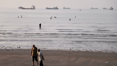 Men walk on the shoreline as people wade in the water in the Strait of Hormuz off Bandar Abbas, Iran, June 1, 2026.