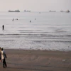 Men walk on the shoreline as people wade in the water in the Strait of Hormuz off Bandar Abbas, Iran, June 1, 2026.