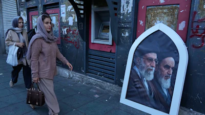 Pedestrians walk past a poster showing slain Iranian Supreme Leader Ayatollah Ali Khamenei, left, and the late revolutionary founder Ayatollah Khomeini, Islamic Revolution square, Tehran, June 14, 2026.