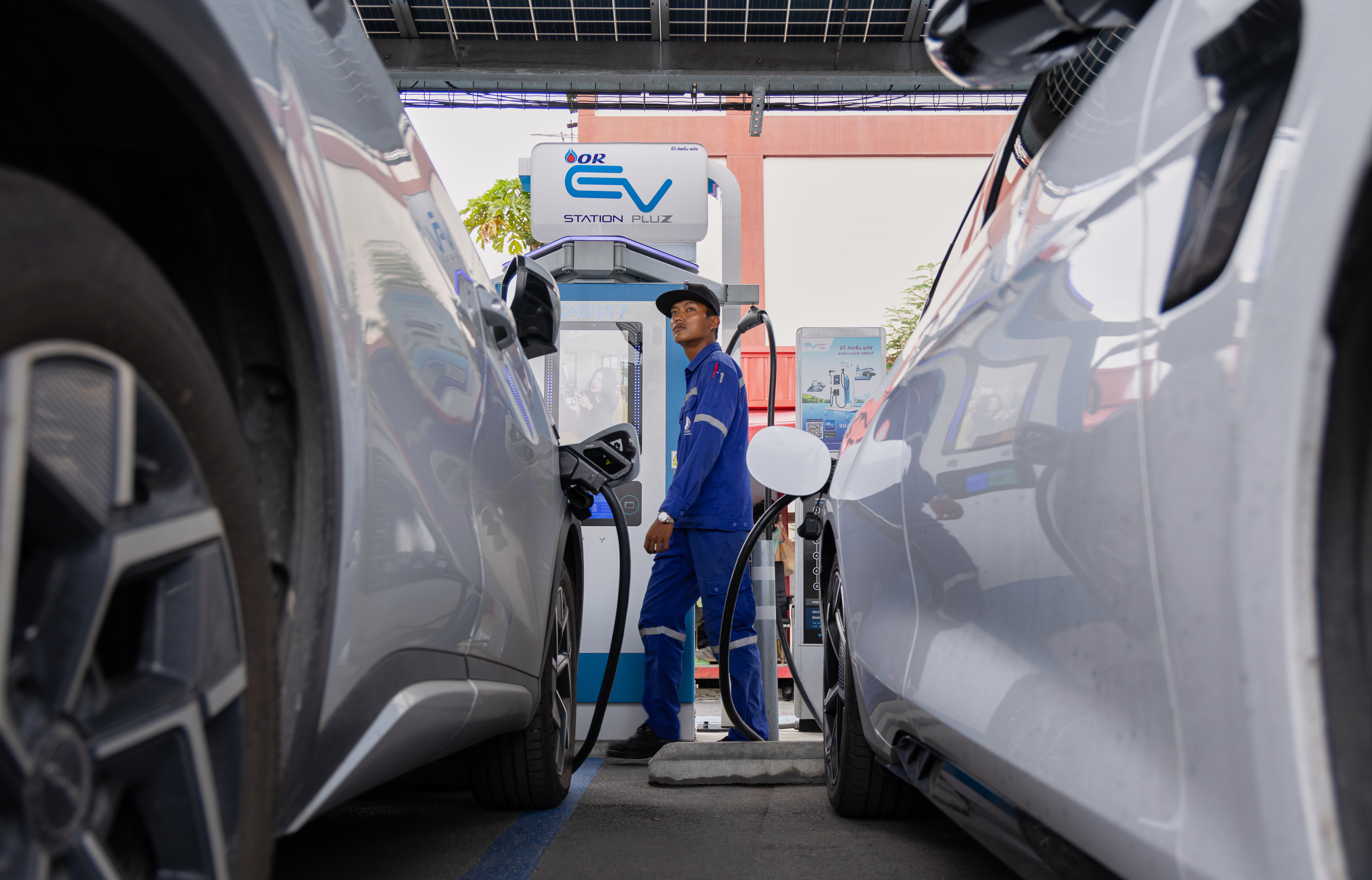 Khatawut Junsongsaeng, a charging station manager, walks past two Chinese-made electric vehicles at a parking lot in Bangkok, Thailand on June 4, 2026.
