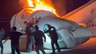 A passenger, top, jumps out of a plane after it crashed on a highway as other people help Tuesday, June 16, 2026, in Laredo, Texas.