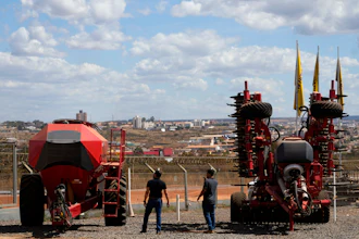 Salesmen walk among agricultural machinery displayed at an equipment dealership, Brasilia, Brazil, July 22, 2026.