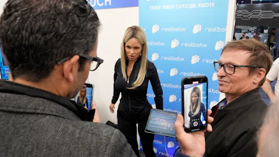 A Realbotix humanoid robot, center, speaks with attendees at a Realbotix booth during the CES tech show Jan. 8, 2025, in Las Vegas.