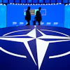 Two men walk past the NATO logo during the NATO Defense Industry Forum at the NATO summit in Ankara, Turkey, Tuesday, July 7, 2026.