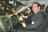 Hiroshi Okuda, then, president of Toyota Motor Corp., smiles as he sits at the steering wheel of the 'Aristo,' Toyota's remodeled sports sedan during a press conference at a Tokyo hotel, Aug. 27, 1997.