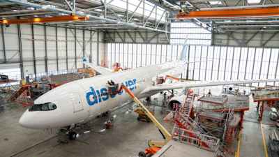 Flydubai aircraft undergoing maintenance in industrial hangar with orange support equipment and scaffolding