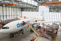 Flydubai aircraft undergoing maintenance in industrial hangar with orange support equipment and scaffolding