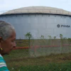 A woman walks near of a oil storage tank of Venezuela's state-run oil company, PDVSA in Cabimas, Venezuela, Tuesday, Sep. 1, 2026.
