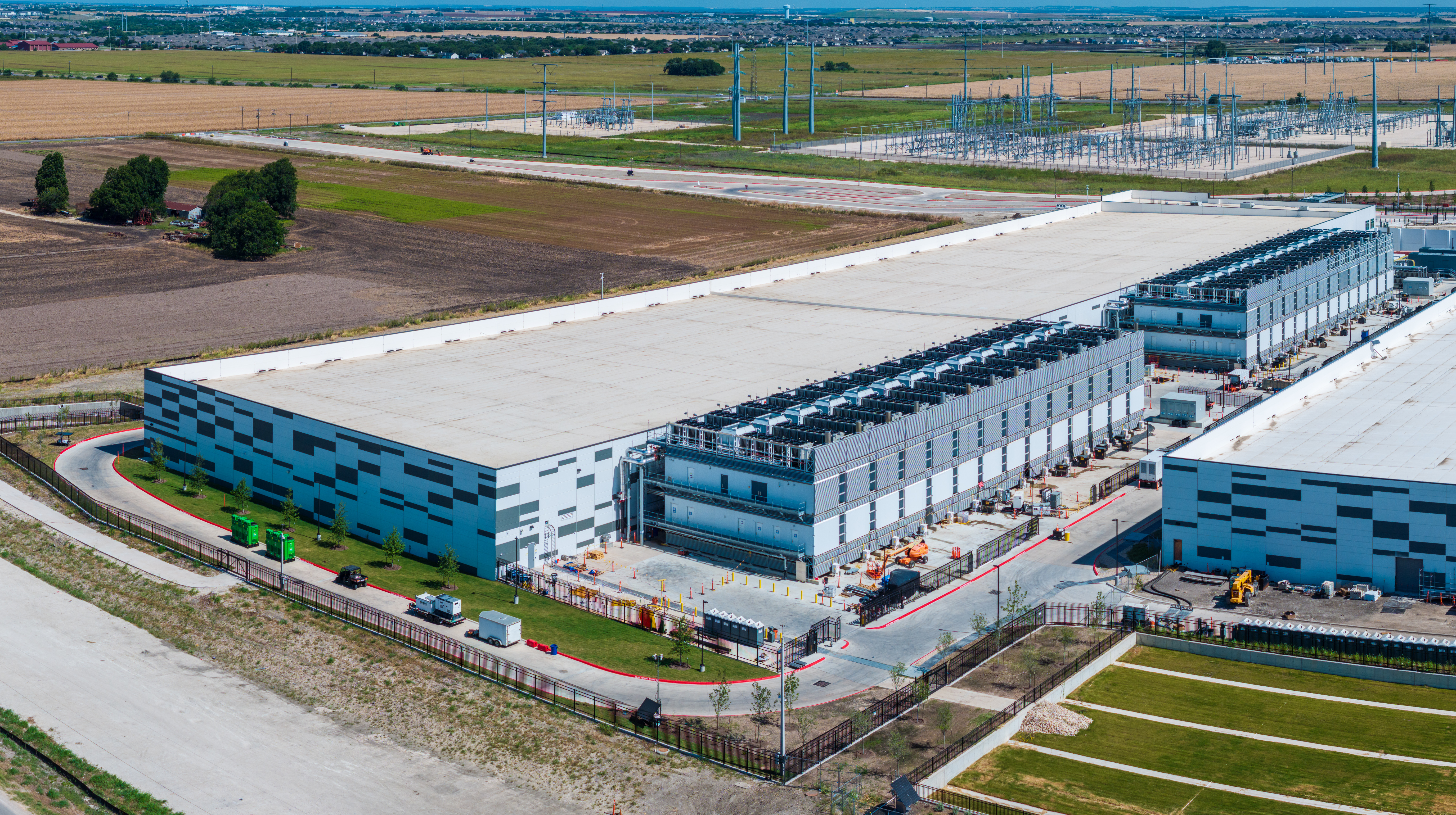 Aerial view of modern industrial warehouse and logistics facility complex with blue and white buildings in rural landscape