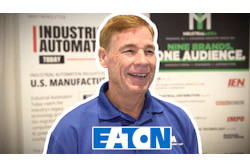 Professional man in blue polo shirt smiling at industrial automation event with Eaton logo visible