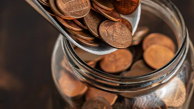 Copper pennies pouring into a glass jar for savings and financial planning