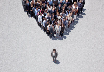 Aerial view of business professionals arranged in triangle formation with single leader standing below, representing organizational hierarchy and team structure