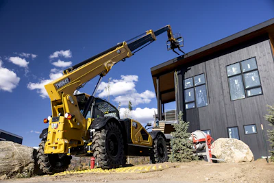 Yellow Liebherr telehandler crane lifting materials on a construction site with modern building in background
