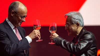 Two professionals toasting with glasses of whiskey against a red background during a formal event