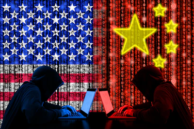 Silhouetted hackers at laptops facing each other against US and Chinese flag backgrounds with binary code and stars, representing cyber conflict.