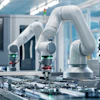 White collaborative robotic arms assembling electronic circuit boards in a modern manufacturing facility