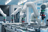 White collaborative robotic arms assembling electronic circuit boards in a modern manufacturing facility