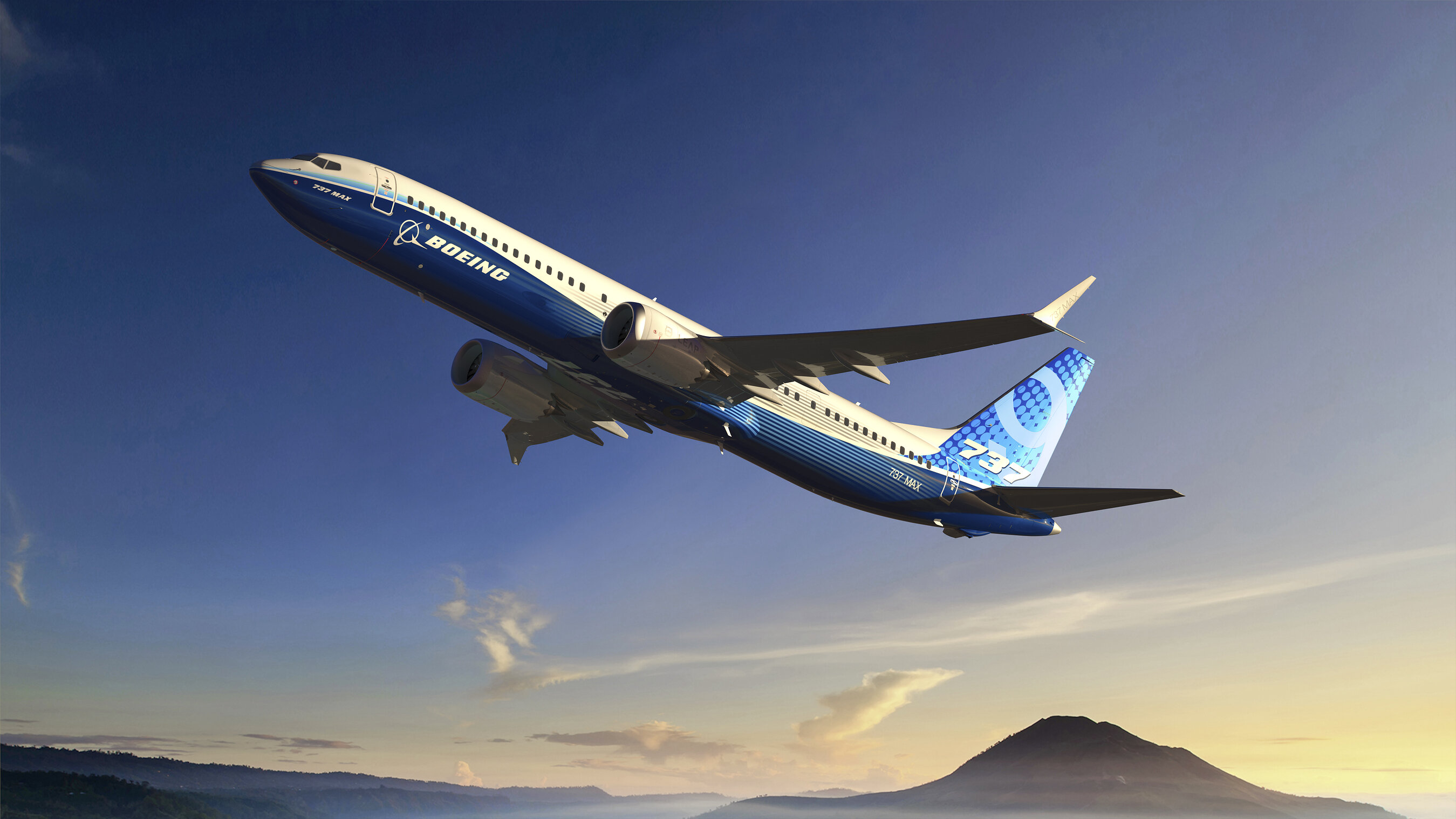 Boeing 737 aircraft in flight over mountainous landscape at sunset