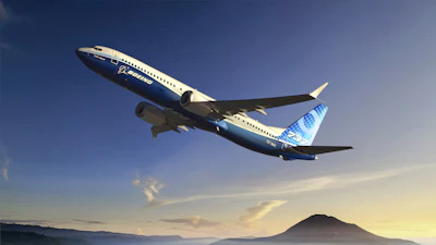 Boeing 737 aircraft in flight over mountainous landscape at sunset
