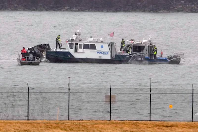 Police boat with personnel conducting water rescue operations near shoreline barrier