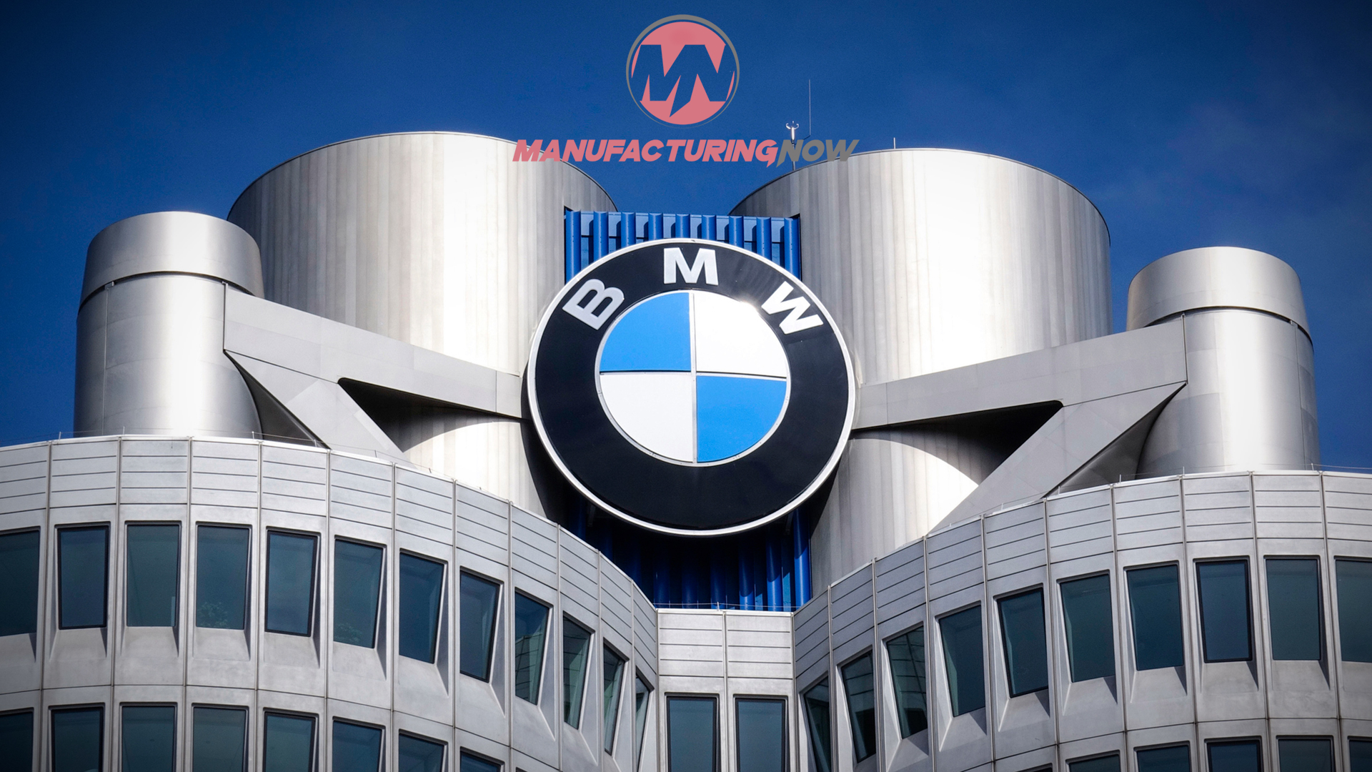 BMW logo mounted on modern building with cylindrical towers and blue sky background