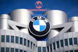 BMW logo mounted on modern building with cylindrical towers and blue sky background