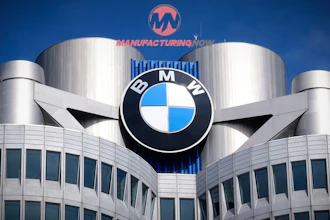 BMW logo mounted on modern building with cylindrical towers and blue sky background