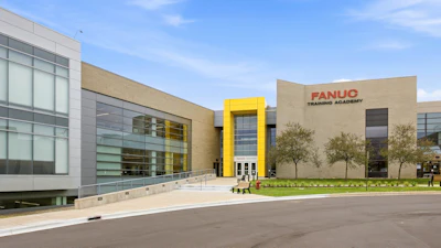 Modern FANUC Training Academy building with glass and tan facade, featuring yellow accent entrance and landscaping